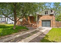 Charming brick home with a modern garage door and mature tree, set on a well-maintained lawn at 2626 Tennyson St, Denver, CO 80212