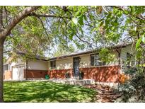 Charming ranch style home featuring a well manicured lawn, brick accents, and mature shade tree at 6470 Field St, Arvada, CO 80004
