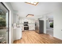Bright kitchen features stainless steel appliances, wood floors, and a garden window at 15892 E Arkansas Pl, Aurora, CO 80017