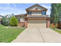 Inviting two-story home featuring a two-car garage, brick accents, and mature landscaping at 19937 E Loyola Pl, Aurora, CO 80013