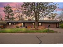 Charming brick ranch-style home featuring a well-maintained front yard and attractive landscaping at dusk at 8750 W 8Th Ave, Lakewood, CO 80215
