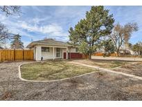 Charming single story home with a well manicured lawn and a large tree, fenced in yard at 1277 Wabash St, Denver, CO 80220