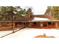 Charming single-story home with a red-railed porch and a brick chimney, surrounded by snow-covered landscape at 17720 Canterbury Dr, Monument, CO 80132