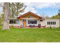Charming home featuring a wooden porch, lush green lawn, and beautiful natural light at 9445 Lykins Pl, Longmont, CO 80503