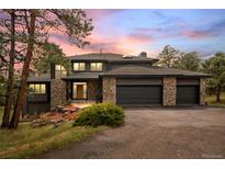 Striking two-story home with a three-car garage and stone accents at dusk at 1423 Belford Ct, Evergreen, CO 80439