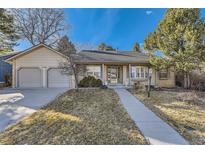 Charming ranch-style home with a well-manicured lawn and two-car garage under a clear blue sky at 5749 S Lansing Way, Englewood, CO 80111