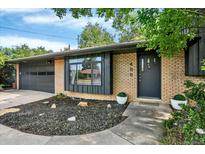 Charming front exterior of a brick home with a manicured yard, dark door, and a two car garage at 400 S Hoyt St, Lakewood, CO 80226