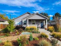 Charming home with a cozy front porch and beautifully landscaped front yard showcasing vibrant plants and a welcoming walkway at 1960 Wabash St, Denver, CO 80220