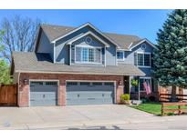 Charming two-story home with a brick and siding exterior and a well-manicured front yard, plus a three car garage at 14533 W 69Th Pl, Arvada, CO 80004