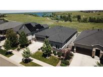 Scenic aerial view of modern homes with solar panels and a serene lake backdrop on a sunny day at 26741 E Peakview Pl, Aurora, CO 80016