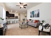 Spacious living room with stylish furniture, plush carpeting, and a modern ceiling fan at 7222 Aspen Brook Ave, Frederick, CO 80530