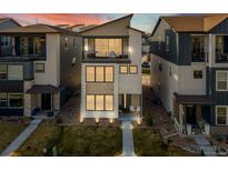 Modern two-story home with stone accents, a balcony, manicured lawn, and beautiful landscaping at 12242 W 56Th Pl, Arvada, CO 80002