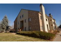 Exterior of a multi-story condo building featuring stone accents, siding, and a well-manicured lawn at 7369 S Gore Range Rd # 103, Littleton, CO 80127