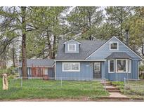 Charming blue two-story home with a well-maintained front yard and mature trees at 7957 Elm St, Louviers, CO 80131