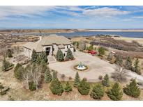 Stunning aerial view of the home, fountain, and surrounding landscape with lake views at 7615 Lemon Gulch Way, Castle Rock, CO 80108