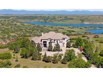 Stunning home with fountain and circular driveway, surrounded by mature trees and a lake backdrop at 7615 Lemon Gulch Way, Castle Rock, CO 80108