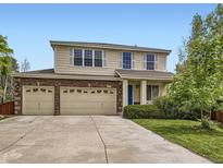 Charming two-story home showcasing a brick facade, three-car garage, landscaped yard, and a welcoming blue front door at 13244 Kearney St, Thornton, CO 80602