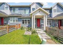 Charming townhome featuring a red front door, covered porch, and small front yard with wooden fence at 6211 W 28Th Ct, Wheat Ridge, CO 80214