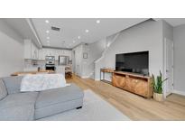 Bright open-concept living room featuring hardwood floors, a modern kitchen, and a comfortable sectional sofa at 6211 W 28Th Ct, Wheat Ridge, CO 80214