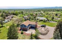 Expansive home on large lot featuring a front circular driveway, landscaped grounds, and mountain views in the distance at 7930 Alkire St, Arvada, CO 80005