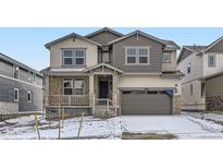 Charming two-story home featuring a stone facade, welcoming front porch, and attached two-car garage at 585 Twilight St, Erie, CO 80516