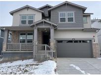 Two-story home featuring varied gray siding, stone accents, covered front porch, and two-car garage, offering classic curb appeal at 585 Twilight St, Erie, CO 80516