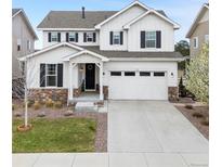 Charming two-story home with a white exterior, stone accents, a two-car garage, and manicured landscaping at 7756 S Eaton Park Ct, Aurora, CO 80016