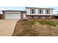 Charming two-story home featuring a brick and white siding, attached garage, and well-manicured front yard at 10930 Albion Ct, Thornton, CO 80233