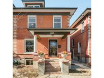 Charming two-story brick home with a covered front porch and colorful flower planters at 1003 N Emerson St, Denver, CO 80218
