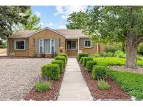 Charming brick home featuring lush landscaping, inviting walkway, and mature shade trees at 2690 Magnolia St, Denver, CO 80207