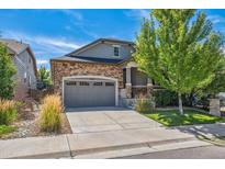 Beautiful home with a stone facade, a two-car garage, and manicured landscaping under a bright blue sky at 13632 W 64Th Dr, Arvada, CO 80004