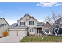 Charming two-story home with a manicured lawn, a two car garage, and solar panels at 6681 Secrest Cir, Arvada, CO 80007