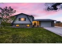 Charming two-story home with landscaped lawn, covered porch, and attached two-car garage at dusk at 1062 Jasper St, Aurora, CO 80011