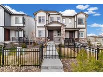 Attractive townhome featuring a stone accent facade, a well-maintained lawn, and a charming fenced-in yard at 12570 Boggs St, Parker, CO 80134