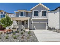 Charming two-story home featuring a stylish gray exterior, landscaped yard, and an attached two-car garage at 305 Welded Tuff Trl, Castle Rock, CO 80104