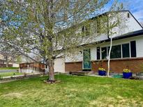 Charming two-story home with green lawn, brick accents, attached garage, and beautiful trees at 4934 S Flower Way, Littleton, CO 80123