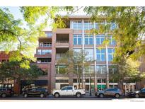 Modern multi-story condo building featuring large windows and balconies, surrounded by lush green trees and sidewalks at 1720 Wazee St # 3B, Denver, CO 80202