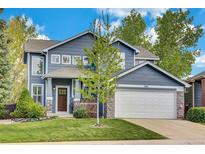 Charming two-story home featuring a blue exterior, stone accents, and a well-manicured lawn at 10882 Bullock Ct, Parker, CO 80134