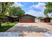 Charming home featuring a spacious driveway, green siding, brick accents and mature trees at 850 Idalia Cir, Aurora, CO 80011