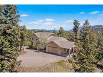 Secluded home with an attached two-car garage, surrounded by lush forest and mountain views at 6252 King Dr, Evergreen, CO 80439