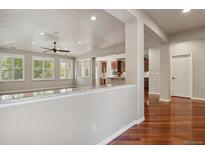 Bright living room featuring hardwood floors, natural light, and open floor plan to kitchen and adjacent rooms at 2485 Vale Way, Erie, CO 80516