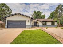 Charming home featuring a well-maintained lawn, complemented by tasteful rock landscaping and a painted two-car garage door at 1819 S Nile Ct, Aurora, CO 80012