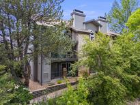 Condo exterior with stone accents, mature trees, and private balconies under a blue sky at 2575 S Syracuse Way # K201, Denver, CO 80231