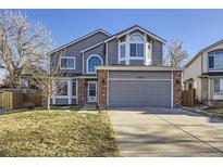 Charming two-story home with gray siding, brick accents, manicured lawn, and attached two-car garage at 13322 Marion St, Thornton, CO 80241