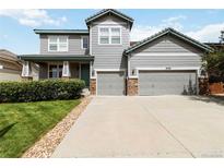 Charming two-story home with a well-manicured lawn, two-car garage and appealing gray siding with stone accents at 10730 Hillrose St, Parker, CO 80134