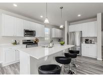 Bright kitchen features white cabinetry, stainless steel appliances, and a large island with seating at 12941 Delaware St, Westminster, CO 80234