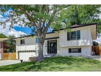 Charming two-story home with a well-maintained lawn and mature tree providing shade at 2221 S Arbutus Ct, Lakewood, CO 80228