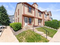 Inviting townhome with red and tan exterior, featuring a charming front entrance and well-maintained landscaping at 14465 E Hawaii Cir # A, Aurora, CO 80012