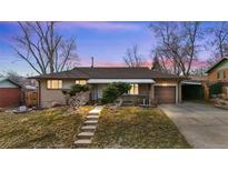 Charming brick ranch home features a well-maintained yard, attached garage, and welcoming entrance at dusk at 2909 S Zurich Ct, Denver, CO 80236