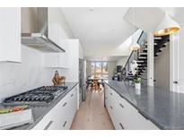 Open-concept kitchen and dining area with modern appliances, sleek cabinets, and contemporary lighting at 5125 W 29Th Ave # 5, Denver, CO 80212